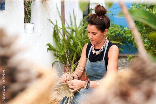 Front view of Hispanic woman weaving a basket with esparto fibers. Manual work, tradition and culture.