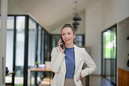 Smart businesswoman stands talking on the phone at the table in the office.