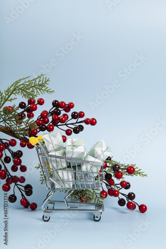 caddy filled with colorful gifts against a luminous sky-blue background and A branch of holly with its red berries