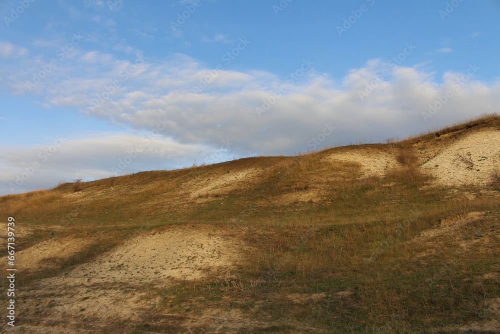 A grassy hill with a cloudy sky A grassy hill with a cloudy sky
