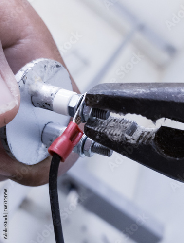 The process of tightening the heater element terminals using combination pliers when repairing chicken hatching machine heaters. photo