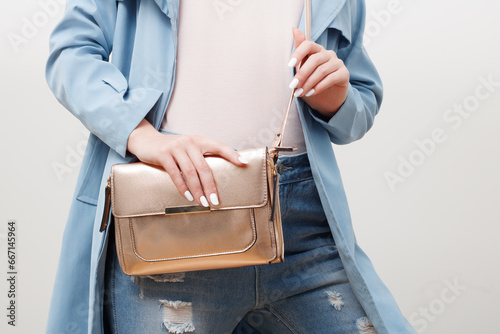 Beauty fashion. Glamorous girl in fashionable clothes, stylish look. Trendy woman in stylish blue coat and jeans with little golden bag clutch . Fashion accessories photo