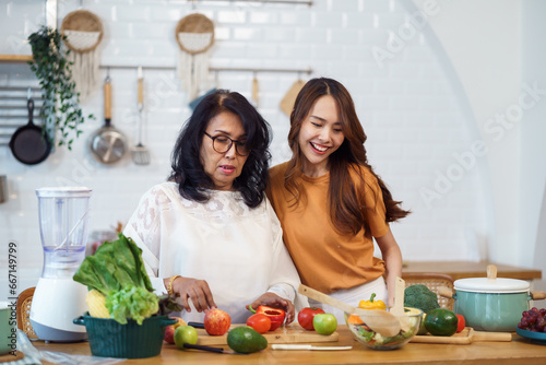 Asian lovely family in the kitchen. Beautiful female enjoy spending leisure time with senior elderly mom while cooking salad and food healthy