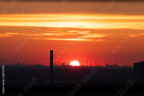 Sun setting over the horizon in Rotterdam. Red light irradiation of the wind farm and the harbour. Sunset in Netherlands