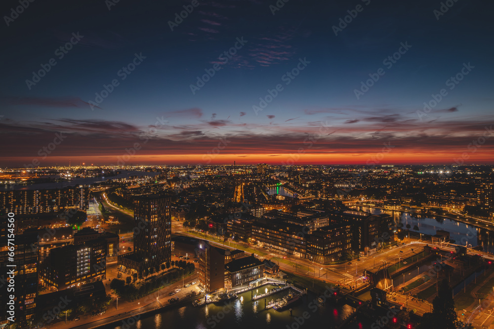 Aerial view of nightlife in the modern city of Rotterdam in the Netherlands. Red glow from the setting sun in the background