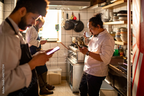Young sushi chef using a smartphone on a coffee break in the restaurant photo
