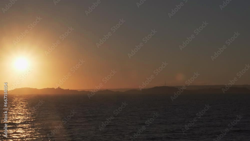 Sunset over an island with sea in foreground Sunset over an island with sea in foreground