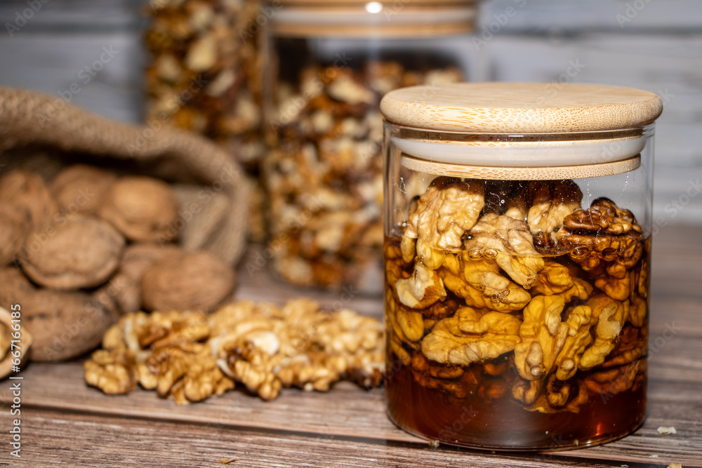 Jar full of walnuts with honey surrounded by whole and peeled walnuts Jar full of walnuts with honey surrounded by whole and peeled walnuts