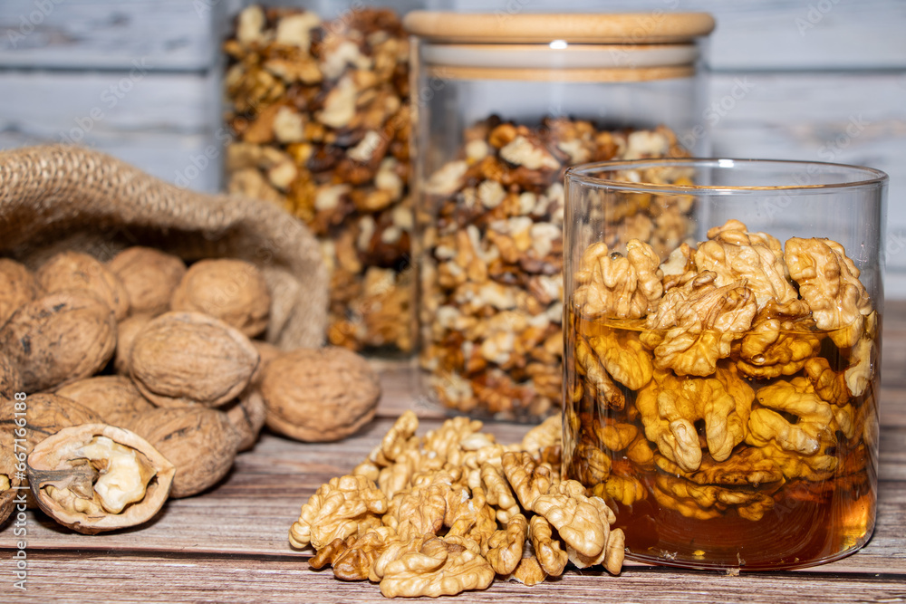 Jar full of walnuts with honey surrounded by whole and peeled walnuts Jar full of walnuts with honey surrounded by whole and peeled walnuts