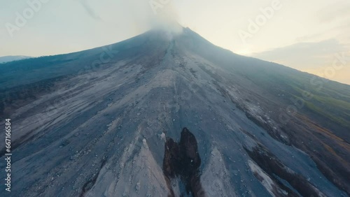 Aerial morning view peak smoke crater active erupting volcano with rocky slopes steam. Powerful wild nature phenomena environmental disaster concept. Volcanic fault with cooling black lava sunrise 4k