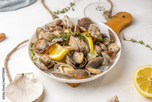 Vongole shellfish appetizer served with lemon and herbs on a light background.