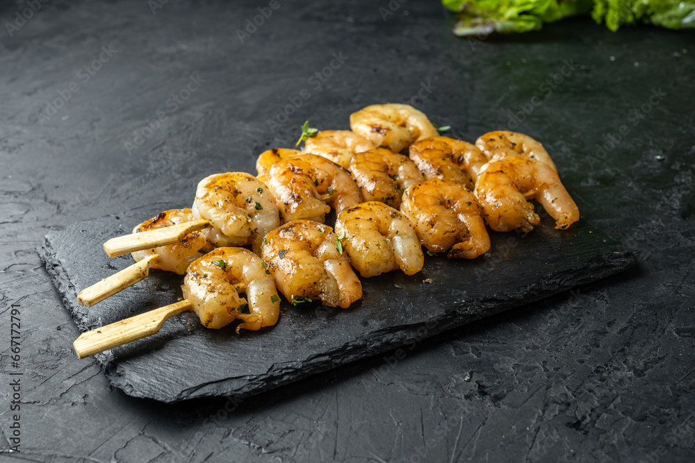 Peeled shrimp skewers, cooked shrimp meat. Dark table. Peeled shrimp skewers, cooked shrimp meat. Dark table.