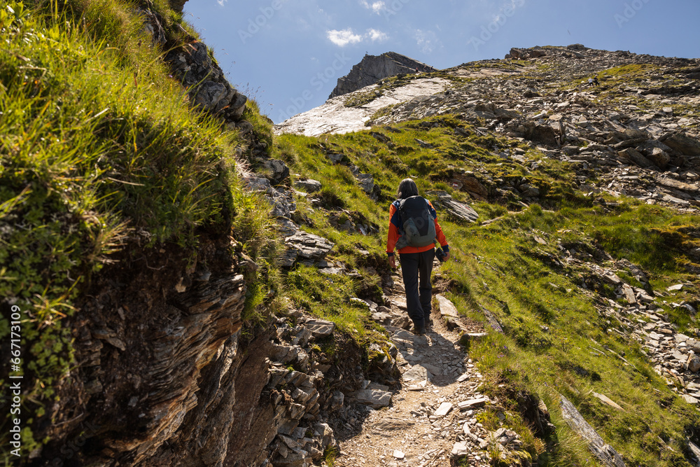 A man with a backpack climbs a scenic rocky trail to a mountain peak, Austria