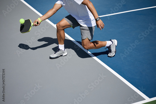 An athlete playing pickleball on a blue and gray court photo