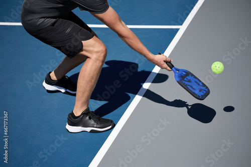 An athlete playing pickleball on a blue and gray court