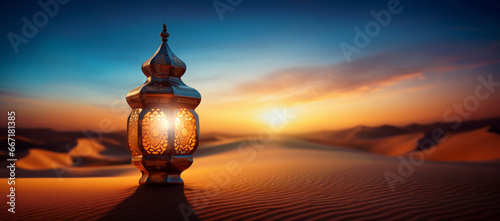 Illuminated golden oriental lantern lying on the sand in the desert dunes at sunset