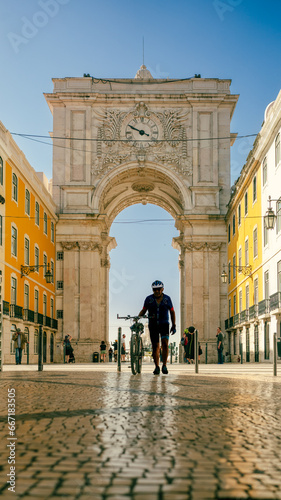 Lisbon, Portugal - May 25, 2023: Silhouette of the bicycle rider walking past the Augusta Arch in Lisbon, Portugal