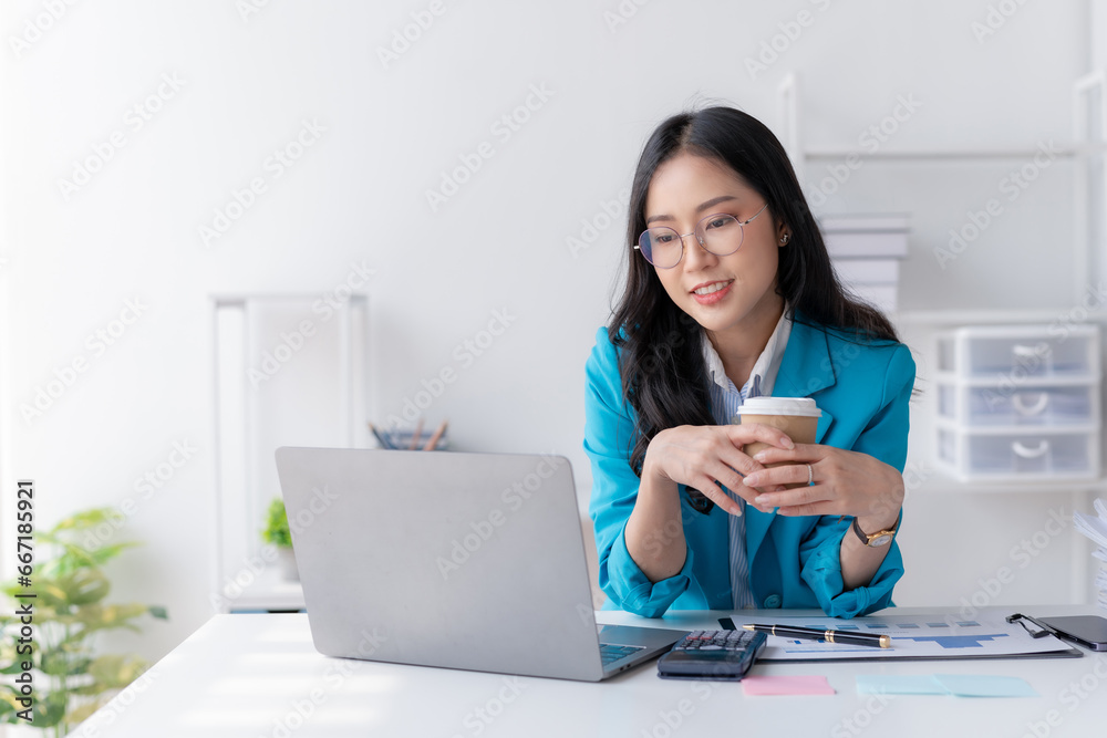 Asian business woman working and checking work with laptop computer while having a comfortable cup of coffee at office. Asian business woman working and checking work with laptop computer while having a comfortable cup of coffee at office.