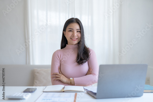 Asian woman sitting with laptop computer at home.