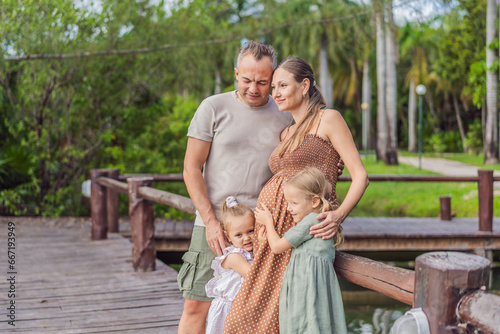 A happy, mature couple over 40 with their two daughters, enjoying a leisurely walk in a park, their joy evident as they embrace the journey of pregnancy later in life