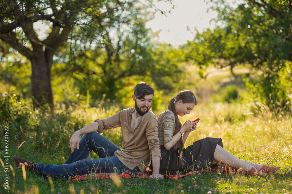 Young couple in nature, a girl with a phone is texting someone