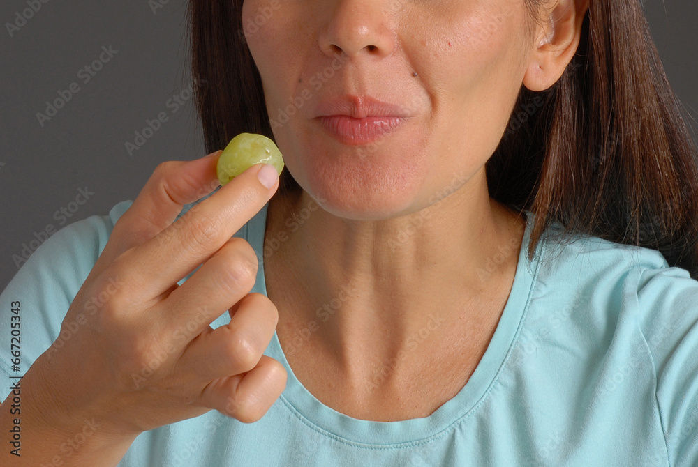 Young woman eating green grape fruits portrait. Young woman eating green grape fruits portrait.