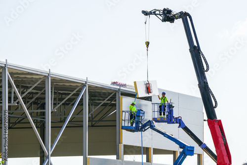 Sandwich panels wall assembly using telescopic boom crane and two self propelled articulating lifts photo