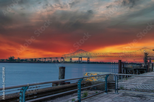 a gorgeous summer landscape along the Mississippi River with the Crescent City Connection bridge over the water with powerful clouds at sunset and a rainbow in New Orleans Louisiana USA photo