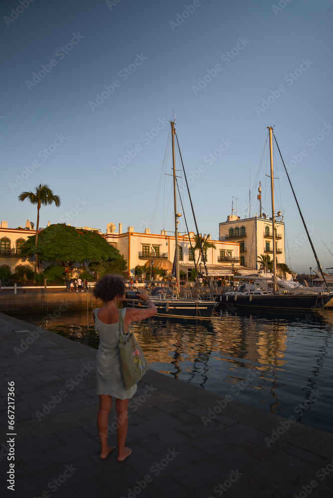 Frau fotografiert mit dem Handy den Hafen in Puerto de Mogan auf der Insel Gran Canaria