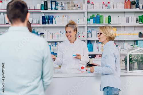 Woman pharmacist working in a pharmacy and selling drugs to a senior woman