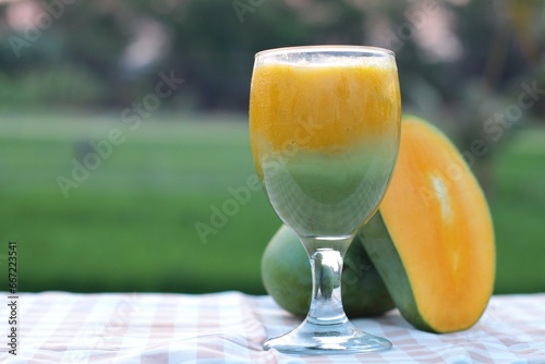 glass of mango juice with macha tea on nature background
