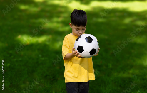 father with son playing on grass football. kid and man foot on ball close up. child cute adorable boy holding in front of face or beating with leg.sunny summer day outside in parc  © Alexandra
