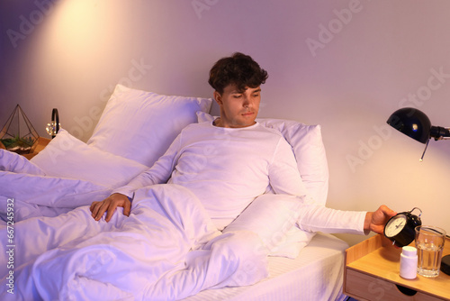 Young man waking up in bed ...