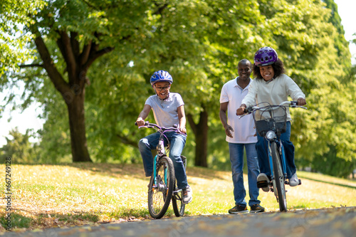 Father teaching his kids riding a bike and looking happy