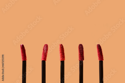 Different lipstick brushes on beige background, closeup