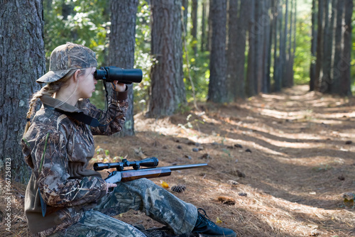 Beautiful young hunter girl looking through binoculars