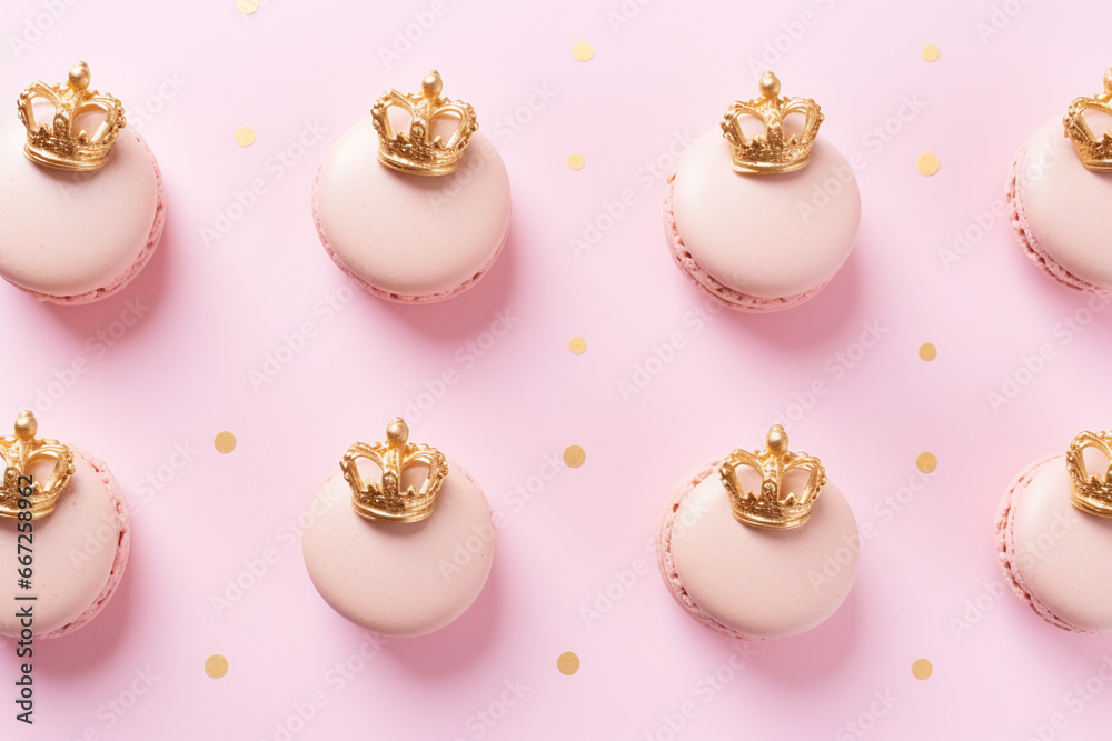 Fototapeta premium Princess themed birthday: delicate pastel pink macarons decorated with a golden crown pattern on a pink background