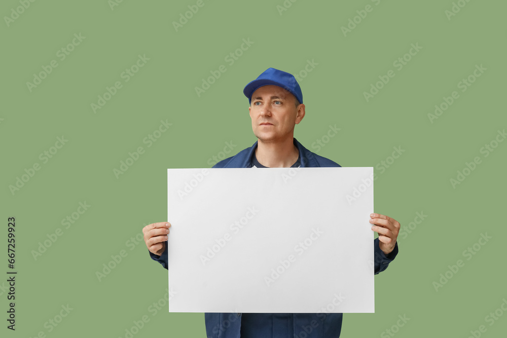 Portrait of male mechanic with blank poster on green background Portrait of male mechanic with blank poster on green background