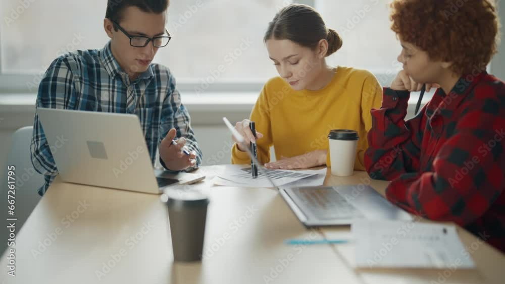 Team of office workers sit at table with documents and laptops and ...
