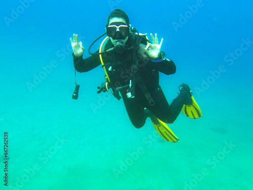 Woman scuba diver alone showing "Ok" signal underwater, "I am Ok", safety check, underwater communication while diving © Gustavo Muñoz