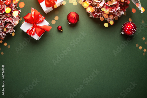 Merry Christmas and Happy Holidays greeting card, frame, banner. New Year. Noel. Red Christmas ornaments and gift on green background top view. Winter xmas holiday theme. Flat lay

