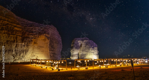 Illuminated outdoor lounge in front of elephant rock erosion monolith standing in the night starlight desert, Al Ula, Saudi Arabia photo