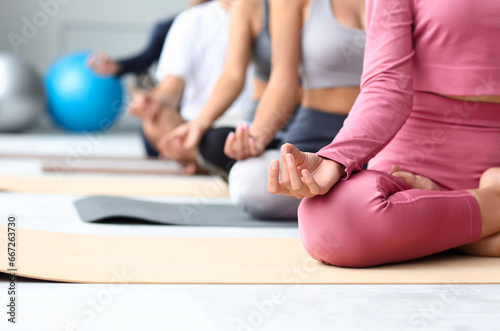 Group of sporty young people meditating in gym, closeup