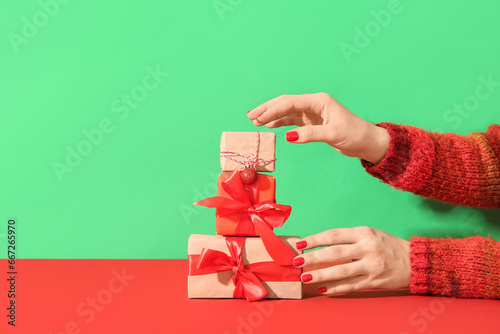 Female hands with red manicure and Christmas gift boxes on green background