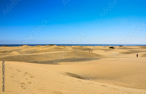 A deliberately out-of-focus shot featuring sandy beach, clear sky, and tranquil horizon evoking peaceful and calm vibes