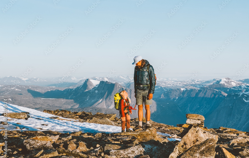 Family father and child climbing mountains together exploring Norway hiking adventure healthy lifestyle outdoor active vacations man with daughter on summit enjoying landscape