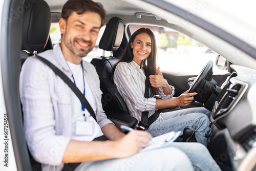 Man instructor examinating brunette lady student in driving school photo