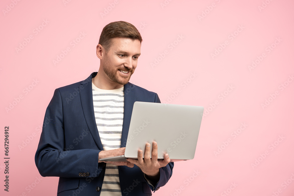 Friendly smiling unshaved man holding laptop, having video call, good idea, problem solution. Stylish optimistic positive man looks like manager, marketer, ceo, executive working in modern office Friendly smiling unshaved man holding laptop, having video call, good idea, problem solution. Stylish optimistic positive man looks like manager, marketer, ceo, executive working in modern office