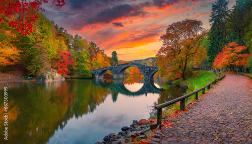 fantastic autumn landscape amazing sunset with colorful sky in azalea and rhododendron park kromlau rakotz bridge rakotzbrucke devil s bridge in kromlau saxony germany photo