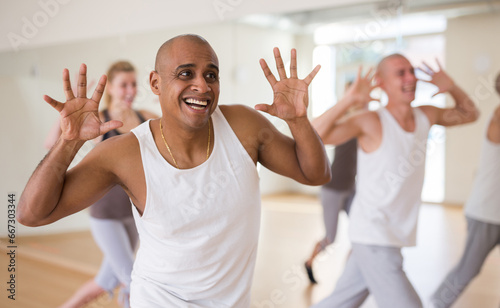 Portrait of cheerful male dancer during group dance workout in fitness center photo